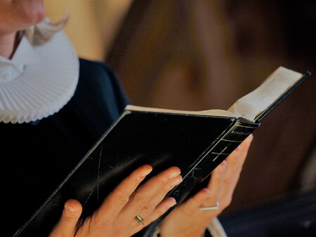 Billede af bibel og præst Billede af præst, der læser fra Bibelen